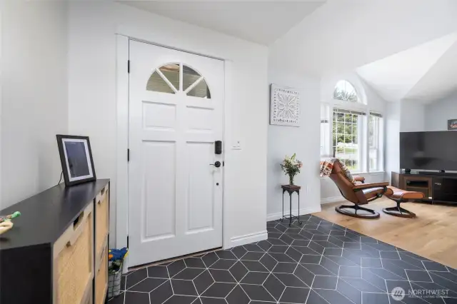 Tiled entryway leads to living room with vaulted ceilings and sunny spaces.