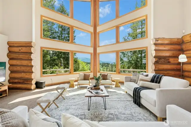 Impressive 2 story living room with cathedral ceilings & walls of glass that frame the idyllic haven beyond