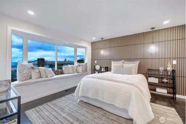 A hotel like primary suite with bay window sitting area with views of downtown Seattle, Bellevue, Lake Washington, and Olympic Mtns