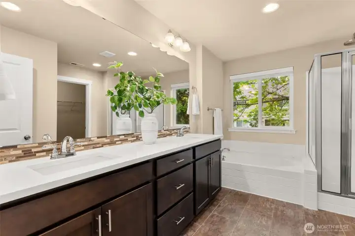 Primary bath featuring dual sinks and a soaking tub with backyard views
