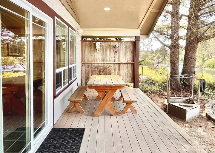 Step outside the main living room to discover   a tranquil covered porch designed for   relaxation and outdoor dining. This intimate   space features a sturdy picnic table, ideal for   al fresco meals or enjoying a morning coffee.   Surrounded by privacy screens, the area   offers a secluded retreat, perfect for   unwinding or entertaining guests in a serene   setting