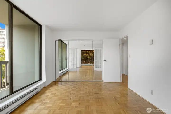 Bedroom 1 with a wall of mirrored closets, floor to ceiling windows and French Doors on one side. Bedroom 1 with a wall of mirrored closets, floor to ceiling windows and French Doors on one side.