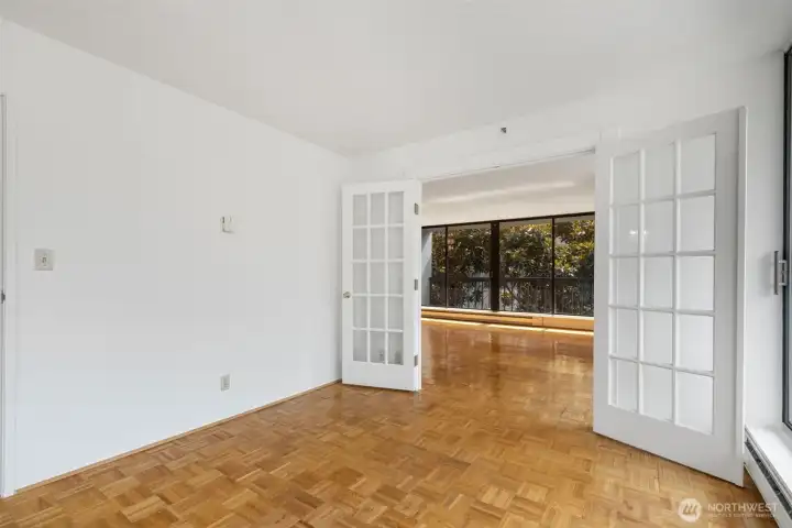 Bedroom 1 with a wall of mirrored closets, floor to ceiling windows and French Doors on one side. Bedroom 1 with a wall of mirrored closets, floor to ceiling windows and French Doors on one side.