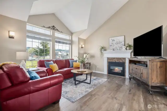 The living room has a vaulted ceiling, huge wall of windows letting the light in, and a refreshed gas fireplace.