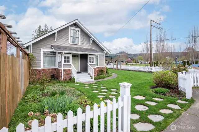 Cobble stone walkway to front door with white picket fencing on this grand corner lot