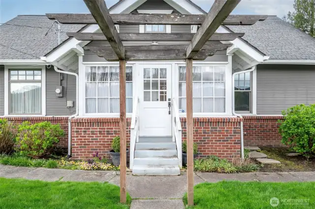 Sidewalks and brick facades wrap the side entry to mud/utility room adorned with an arbor.
