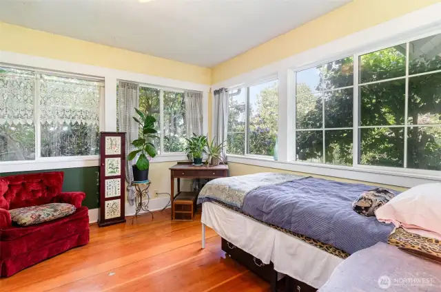 Main floor guest bedroom features elegant French door entry and is surrounded by windows that fill the space with warm natural light.