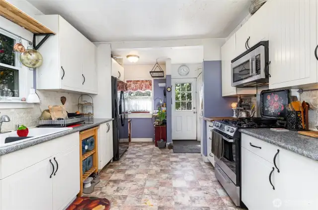 The kitchen features light cabinetry, granite countertops & stainless-steel appliances—blending modern updates with timeless style.