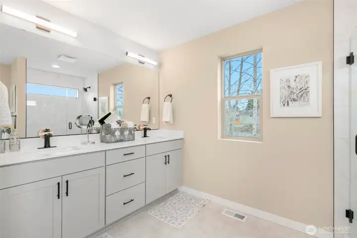 Primary bath with dual sinks, quartz countertop, full sized mirrored wall, walk in shower, freestanding tub and windows for natural light. This bathroom has it all!