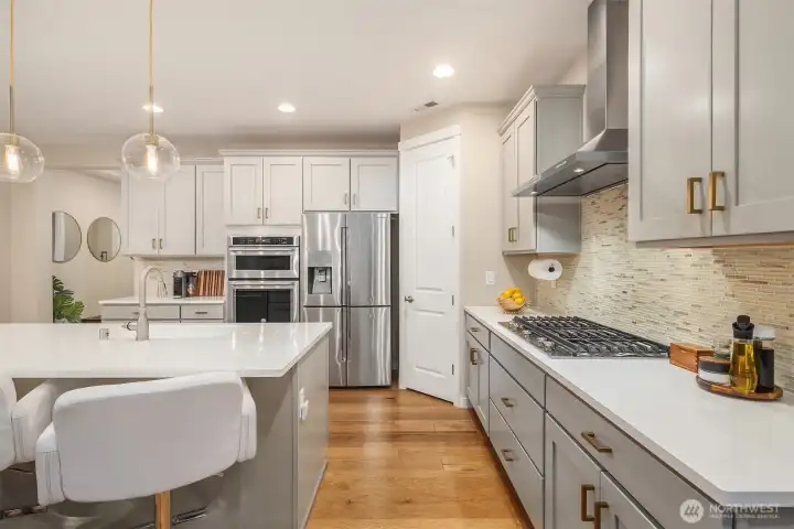 premium features include Quartz countertops, stainless steel appliances, Shaker cabinetry with pull out shelving, counter to cabinets tiled backsplash, gas cooktop, custom pennant lighting and hardwood floors