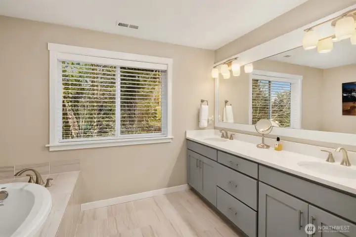 Five piece primary bath features Quartz countertops, undermount sinks, tiled floor, soaking tub and oversized seamless glass shower