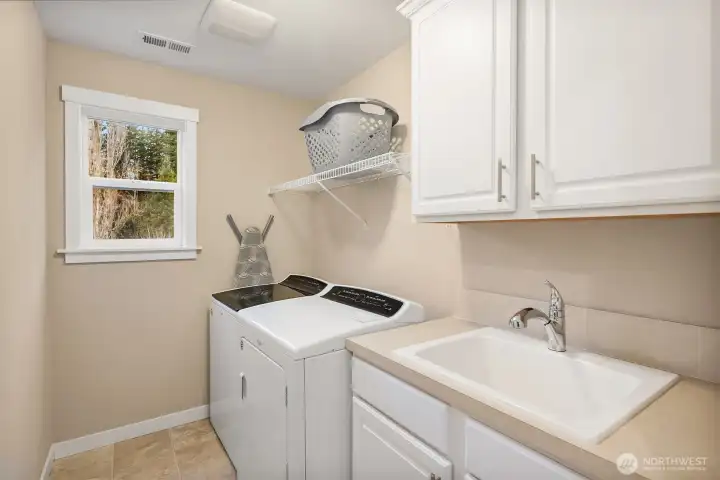 upstairs laundry offers utility sink, storage and linen closet