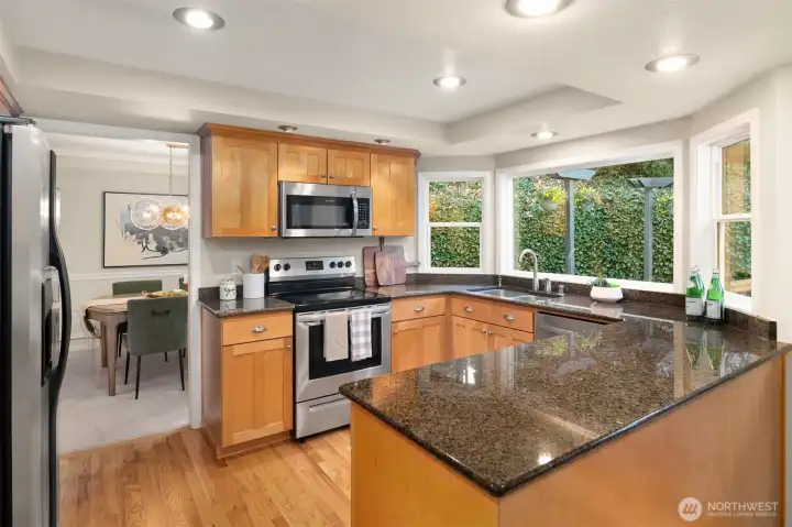 The entertainer’s kitchen is equipped with granite counters, stainless appliances, pull-out shelving, and picture windows looking to peaceful treed views.