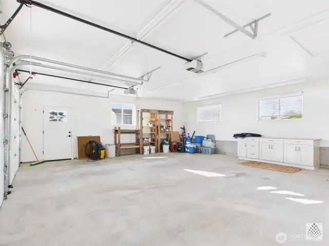 This spacious two-car garage includes a dedicated work area with a built-in work cabinet and windows for natural light.