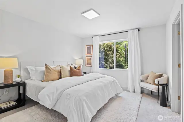 Spacious primary bedroom easily fits a king size bed and looks over peaceful greenbelt.