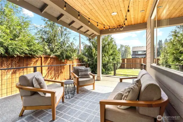 Covered back patio with lights and railings leads to the back yard