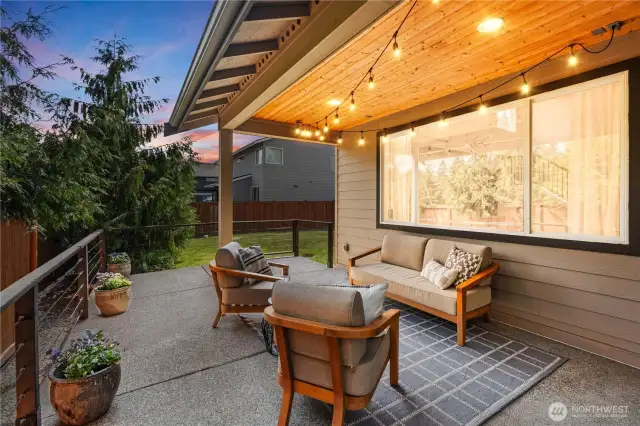 Covered back patio with lights and railings leads to the back yard