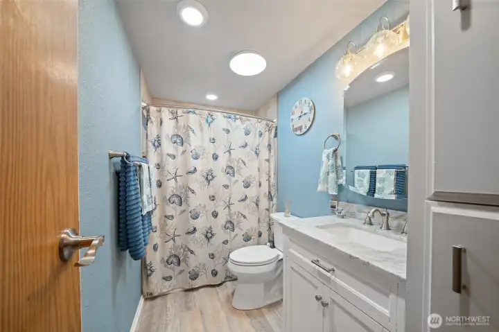 The freshly updated hall bathroom has new LVP flooring and vanity with granite counter