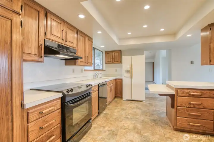 Another kitchen view of cabinetry, counter tops, sink and refrigerator. In the background is the doorway to the primary bedroom all on the main level. Laundry and additional bath are to the left of the kitchen! Another kitchen view of cabinetry, counter tops, sink and refrigerator. In the background is the doorway to the primary bedroom all on the main level. Laundry and additional bath are to the left of the kitchen!