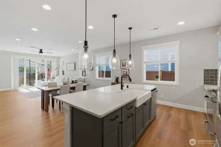 The heart of the home! This massive quartz island offers the perfect vantage point, looking out over the open-concept living space and a stunning wall of windows.