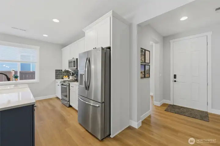 Walk right into a showstopper. This perspective showcases the seamless transition from the front door into a gourmet kitchen packed with upgrades like quartz countertops and soft-close drawers.