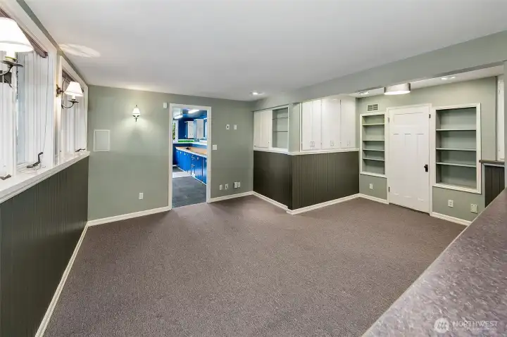 Lower level family room or rec room.  You can see the crafting or planting room in the distance.