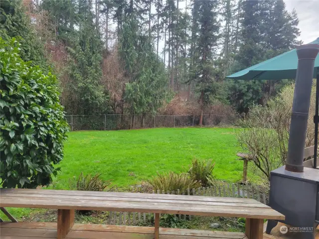 View of the beautiful back yard, the wooded area behind fence is also part of property