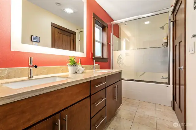 Full bath upstairs w/dual vanity, radiant tile flooring, commode room behind photo