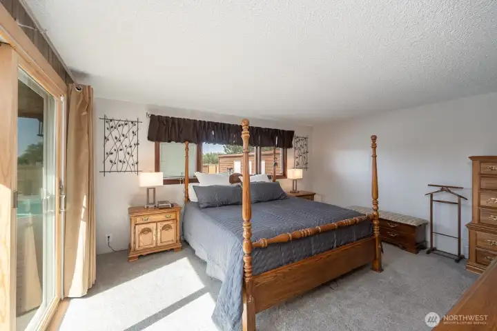 Bright and inviting primary bedroom featuring large windows, outdoor access, and abundant natural light.