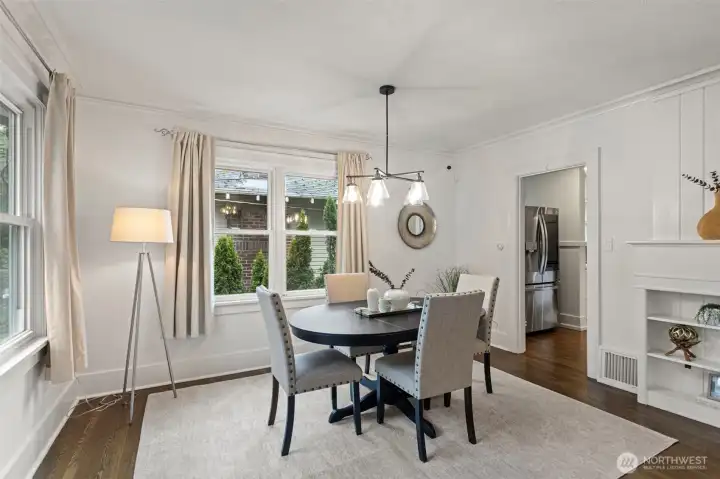 Spacious dining area easily accommodates an extended dining table, offering flexibility for entertaining. An updated light fixture and decorative lap siding above the fireplace add warmth, character, and architectural interest to the space
