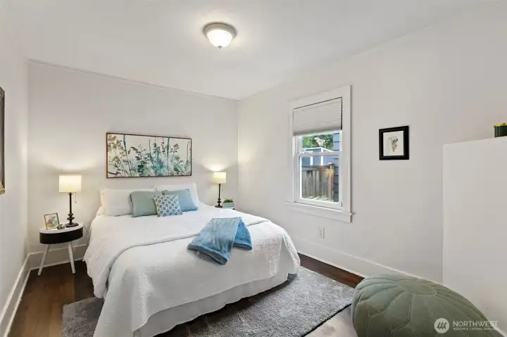 Bright and inviting north-facing bedroom on the main floor with beautifully refinished fir floors, ample closet space, and a spacious layout filled with natural light.