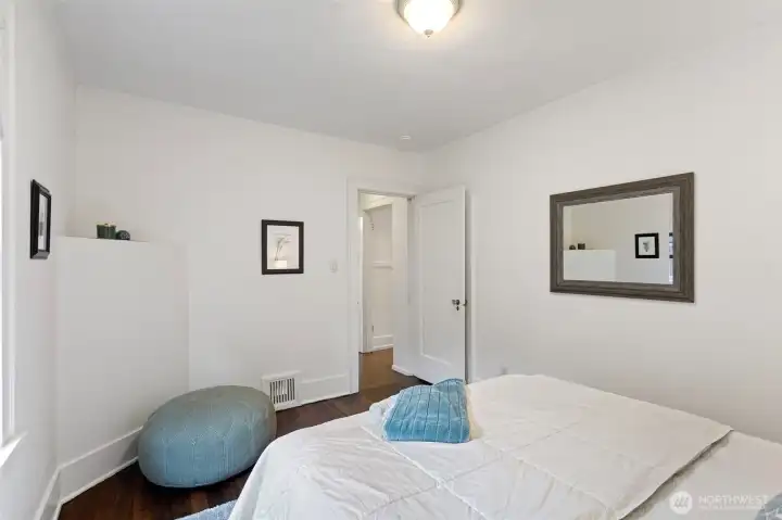 Main-floor north-facing bedroom featuring refinished fir floors, abundant natural light, a spacious closet, and generous room for furnishings and everyday comfort.