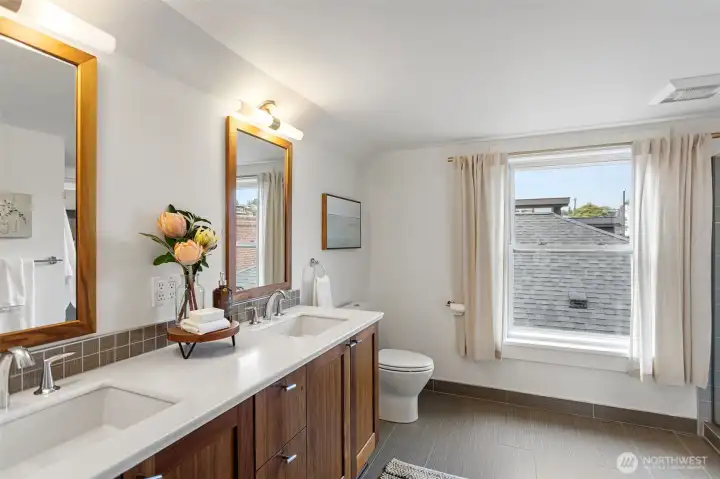 Generously sized bathroom with a double-sink vanity, designer wavy tile backsplash, dual wood-framed mirrors, and heated tile floors with Aube controls, creating a spa-like retreat.
