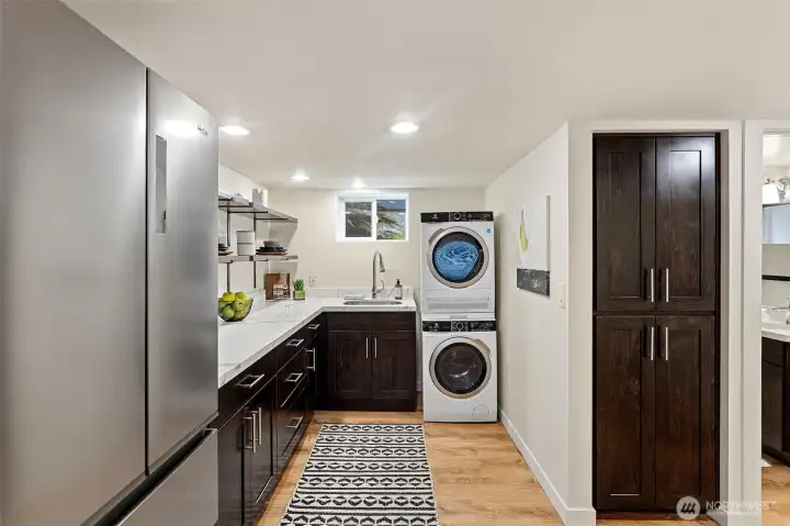 Extensively updated, the lower level features professionally leveled floors with new waterproof flooring, a kitchenette with additional storage cabinetry, a Haier French-door refrigerator with ice and water dispenser, and an Electrolux stackable front-loading washer and dryer.