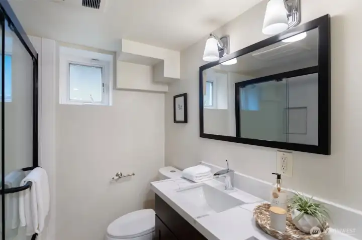 Beautifully renovated full bathroom featuring a new shower door, updated tiled surround, vanity, toilet, and flooring, creating a fresh and modern space.
