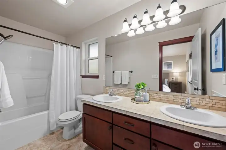 Primary bath, easy to share, with tile counters, double sinks, and great vanity storage space.