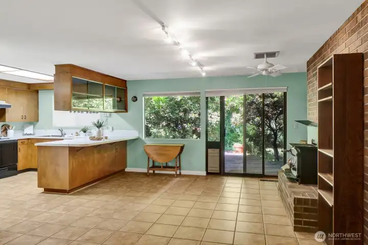 Family room open to the kitchen with tile flooring and a wood burning fireplace insert can heat the whole house. You can sit at the eating bar, or room for a small dining table. Original cabinetry, with all appliances included.