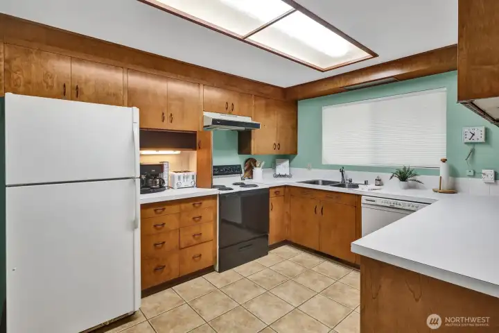 Kitchen with original cabinets, and window looking onto the back yard.