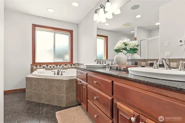 Large ensuite bathroom with dual vanity, granite counters, large jetted tub and ceramic tile flooring Large ensuite bathroom with dual vanity, granite counters, large jetted tub and ceramic tile flooring