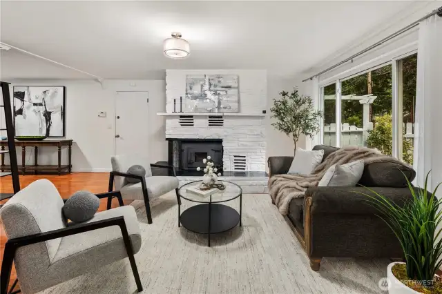 The living room features large windows for letting in lots of light on sunny days and a cozy wood burning fireplace for those rainy winter days