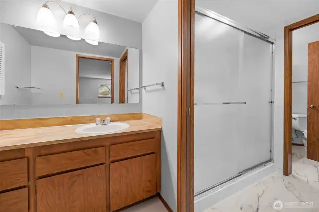 Jack and Jill style bathroom has separate toilet rooms and sinks on both sides of the central walk in shower.