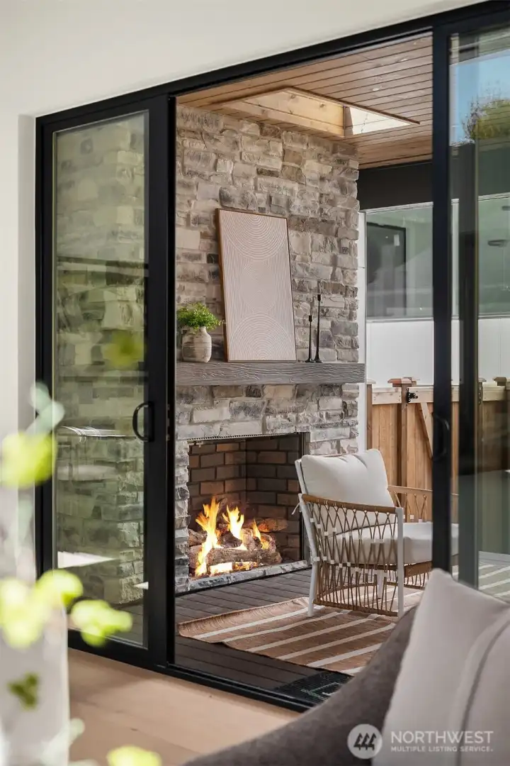 Covered patio designed for year-round enjoyment with floor-to-ceiling stone gas fireplace, infrared heater, and built-in speakers.