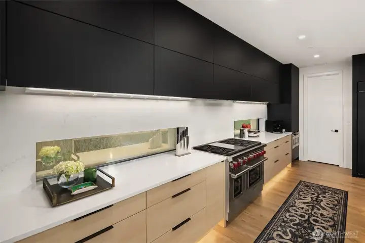 The Wolf range boasts 8 burners, a griddle and double ovens. Love the etched glass in the quartz surround.