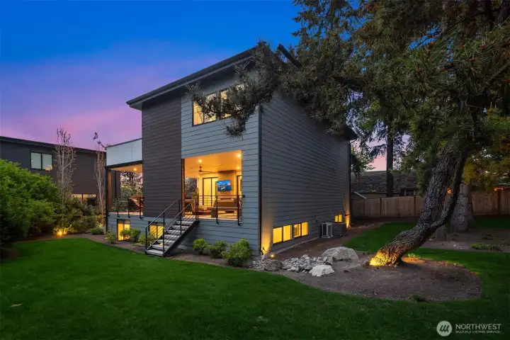 The outdoor space is fully fenced, and boasts a large, flat lawn and mature trees and plantings.