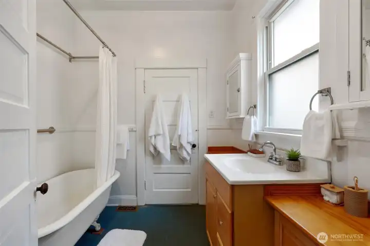 Gracious full bathroom features ample cabinet and counter space, with nods to the home's era with features like the claw-foot tub.