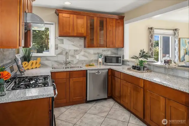 Warm, open kitchen with stainless steel appliances and full-height tile backsplash that adds a modern touch.