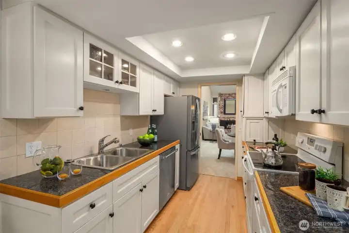 The wider-than-average galley kitchen is bright and spacious, featuring an appliance garage, a French door refrigerator, and newly refinished hardwood floors.