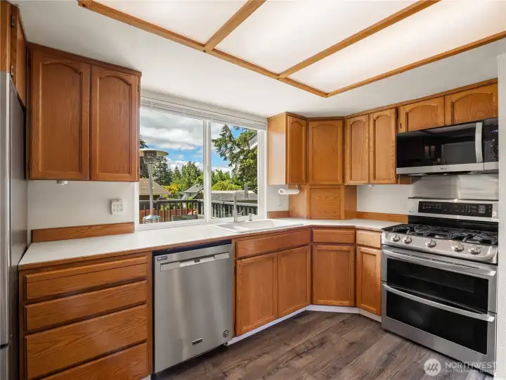 The bright kitchen overlooks the deck and backyard through the large window behind the sink. The bright kitchen overlooks the deck and backyard through the large window behind the sink.