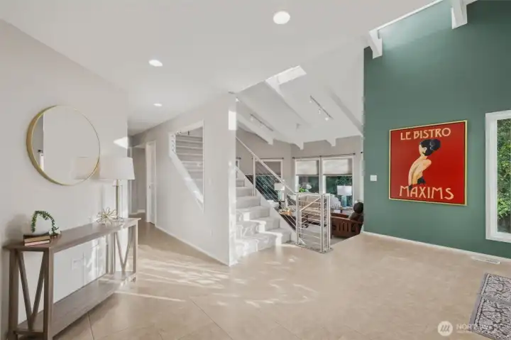 Light-filled entryway with modern finishes, including contemporary cable railing system with sleek metal balusters and wood cap rail and a stylish accent wall leading into the main living areas.