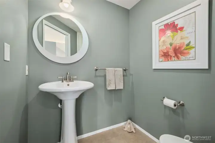 Charming powder room with pedestal sink, round mirror, and tasteful décor.